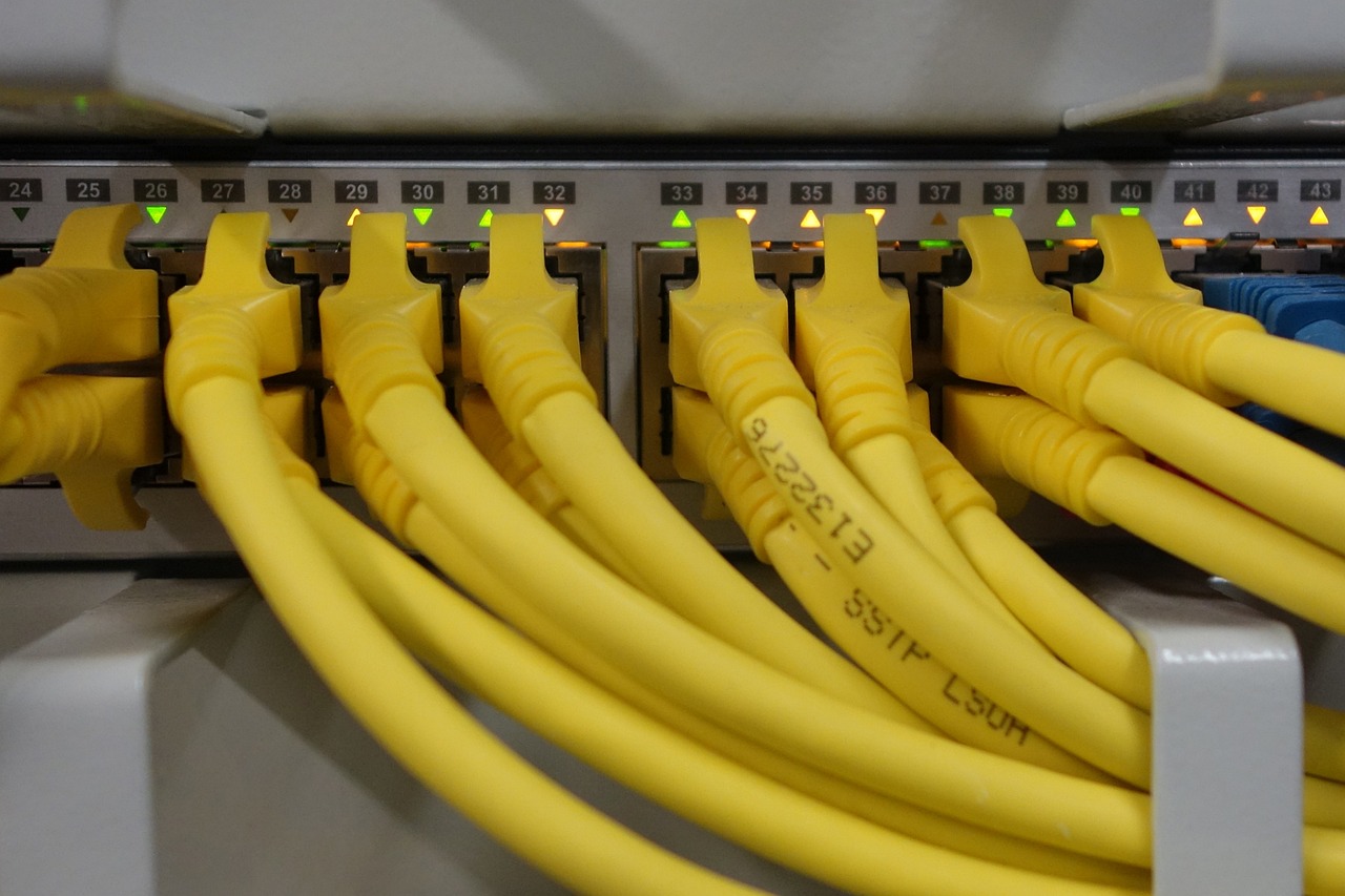 Network patch panel with numbered ports and yellow Cat cable, link lights active